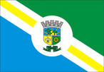 Artigo 3 - A Bandeira do Municpio de Pinhais tambm idealizada pelo Professor Douglas Macarthur de Oliveira Boechat, interpretada heraldicamente pela ESIMPAR - Enciclopdia Simblica Municipalista Paranaense, ser composta de forma retangular, na proporo de 14 (quatorze) mdulos de largura por vinte mdulos de comprimento.  Artigo 4 - A Bandeira compe-se de dois campos iguais em forma de tringulo retngulo escaleno, separados por uma faixa em branco de 03 (trs) mdulos de largura, contendo em seu centro um crculo branco onde  aplicado o braso de armas.  I - O tringulo superior  na cor verde e o inferior  na cor azul.  II - A faixa em branco, carregada de uma sobrefaixa amarela de 01 (um) mdulo de largura, que separa o campo verde do campo azul, parte do ngulo superior direito (lado da adria), seguindo obliquamente at o ngulo inferior esquerdo.  III - A figura geomtrica no centro da Bandeira, em que  aplicado o Braso de Armas, representando o Governo Municipal,  um crculo em branco que simboliza o infinito, visto no ter princpio nem fim.  [...] Os artigos 5 e 6 referem-se a regulamentao do uso do smbolo municipal em premiaes s pessoas que se destacam no Municpio. [...]  Pao Municipal de Pinhais, 18 de maro de 1993.